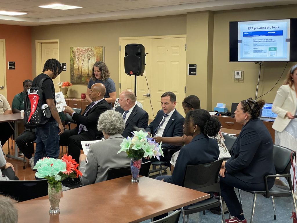Young environmental leader from Elizabeth, NJ, wearing Rutgers air quality sensor backpack, explains how it works to Sen. Booker. Mayor Bollwage, Rep. Menendez, EPA Region Administrator Garcia, and County Commissioner Kowalski.